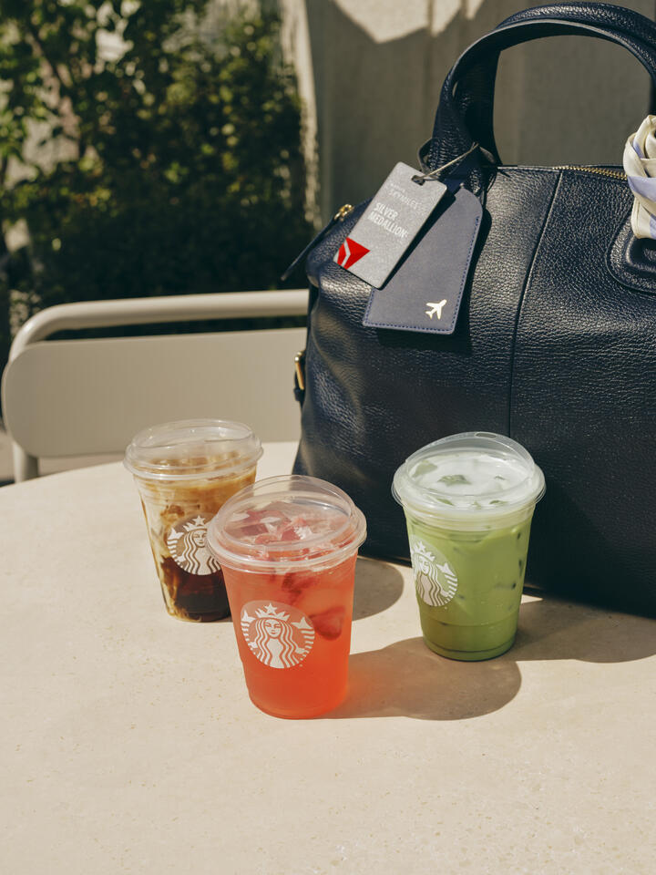 Three iced Starbucks drinks beside a bag with a Delta luggage tag